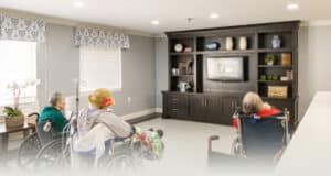 Three ladies in wheelchairs in a common room at Homestead